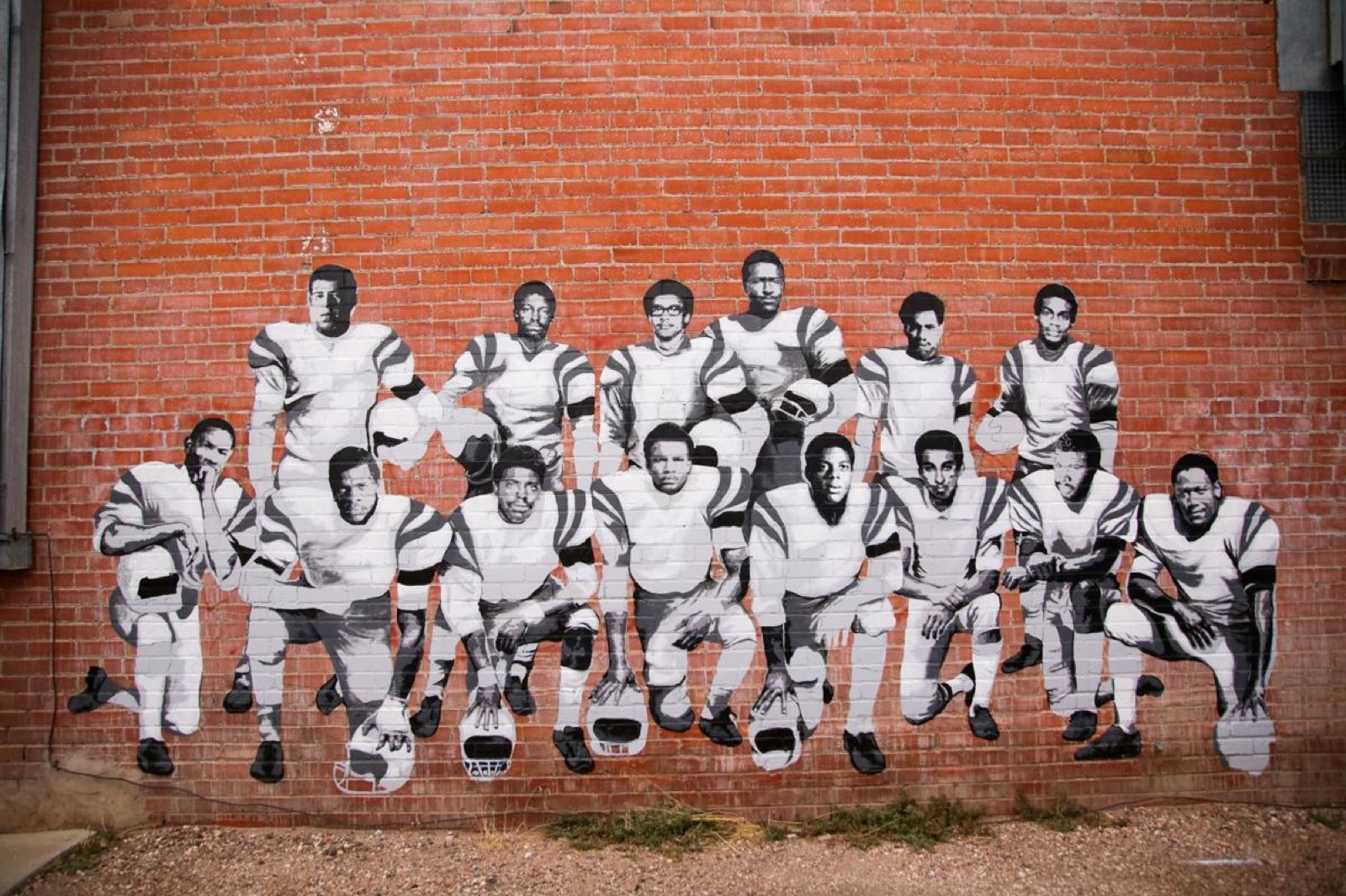 A mural of the fourteen players painted on a brick wall.